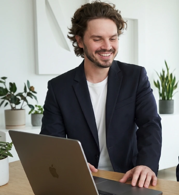 Glimlachende adviseur van Comfort Studio werkt aan een woningrapport op zijn laptop